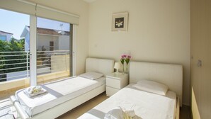 Ein Hotelzimmer mit Balkon, einem Bett, einem Nachttisch mit Lampe und Blumen sowie einem gerahmten Bild an der Wand.