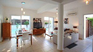 Ein modernes Wohnzimmer mit Fernseher, Sofa und Essbereich.