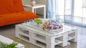 A living room with a white coffee table, orange sofa, and a lamp on a side table. - The Secret to Enjoying Your 5 Star Villa Close to the Beach, Protaras Villa 1484 (Paralimni)