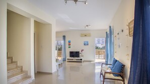 A spacious living area with a staircase, a flat-screen TV, and a blue sofa. - The Secret to Enjoying Your 5 Star Villa Close to the Beach, Protaras Villa 1484 (Paralimni)