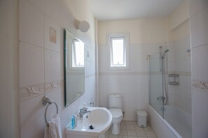 A bathroom with a toilet, sink, and shower.