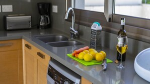 A kitchen with a sink, a coffee maker, a wine bottle, and lemons on a cutting board. - Rent Your 5-star Villa With Private Pool Protaras Villa 1525 (Paralimni)