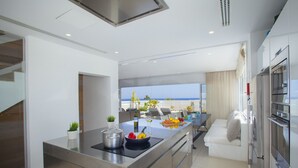 Una cucina moderna con vista sulla spiaggia, un'area pranzo con tavolo apparecchiato per due e forno integrato.