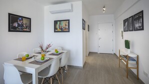 A dining area with a white table, chairs, and a whiteboard. There are framed pictures on the walls and a door in the background. - Fall in Love With This Luxury Beachfront 1386 (Larnaca)