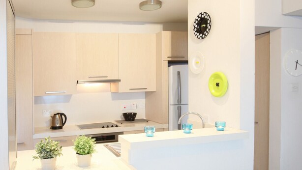 A modern kitchen with white cabinets, a central island with stools, a sink, and a refrigerator. - You Will Love This Luxury Apartment With Stunning Sea Views, Larnaca Apartment 1384 (Larnaca)