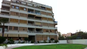 A multi-story residential building with balconies, a central courtyard with grass, and a white wall surrounding the property. - You Will Love This Luxury Apartment With Stunning Sea Views, Larnaca Apartment 1384 (Larnaca)