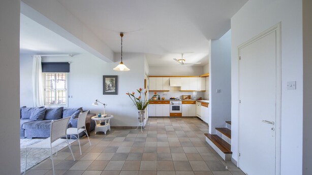 A modern apartment with a living room, kitchen, and staircase. - Seaside Serenity: Protaras Villa 1515 (Paralimni)