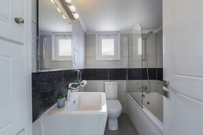 A bathroom with a white sink, toilet, and bathtub, a mirror with lights, and a shower. - Your Beautiful Holiday Villa Minutes From the Beach, Protaras Villa 1492 (Paralimni)