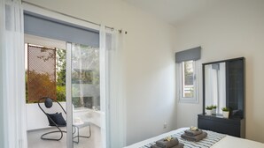 A modern bedroom with a large bed, a small desk, a chair, and a sliding glass door leading to a balcony. - Luxury Holiday Apartment, Protaras Apartment 1417 (Paralimni)