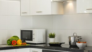 A modern kitchen with white cabinets, a microwave, a stove, and various kitchen items like vegetables and a pot. - Luxury Holiday Apartment, Protaras Apartment 1417 (Paralimni)