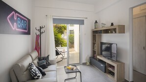 A modern living room with a sofa, coffee table, TV, and a 'BAR' sign on the wall. - Luxury Holiday Apartment, Protaras Apartment 1417 (Paralimni)