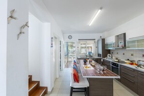 Een magnetron, een oven, een kookplaat, eettafels