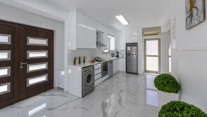 A modern kitchen with white cabinets, a stainless steel refrigerator, and a washing machine. - You and Your Family Will Love This 5 Star Villa With Private Pool, Protaras Villa 1500 (Paralimni)