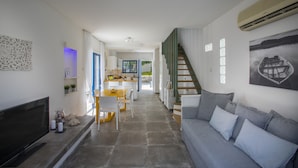 A modern living room with a grey sofa, a flat-screen TV, and a staircase leading to another level. - Imagine Your Family Renting This Luxury Villa Minutes From Fig Tree Bay, Protaras Villa 1426 (Paralimni)