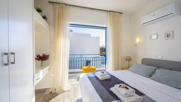 Un cuarto de hotel con cama, balcón y vista al mar.