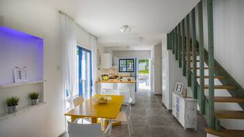 Una cocina moderna con armarios blancos, una isla de madera y un ventanal con marco azul.