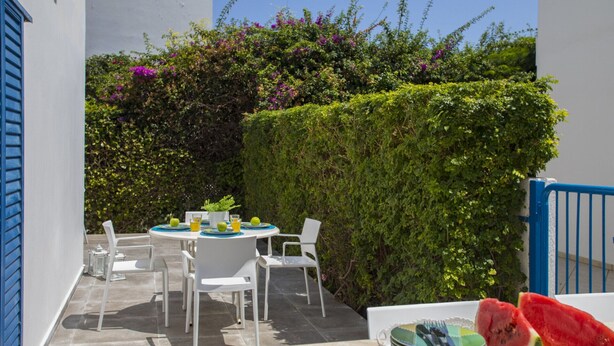 An outdoor patio with a round table and chairs, a small plate with watermelon slices, and a potted plant. - Imagine Your Family Renting This Luxury Villa Minutes From Fig Tree Bay, Protaras Villa 1426 (Paralimni)
