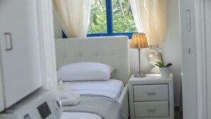 A bedroom with a bed, a bedside table with a lamp and a plant, and a window with curtains. - Imagine Your Family Renting This Luxury Villa Minutes From Fig Tree Bay, Protaras Villa 1426 (Paralimni)