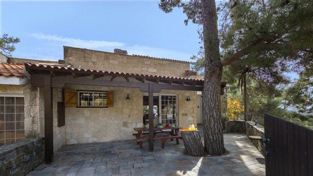 A stone building with a tiled roof, a wooden pergola, and a stone patio with a table and chairs. - You and Your Family Will Love This 5 Star Villa With Forest Views, Limassol Villa 1001 (Platres)