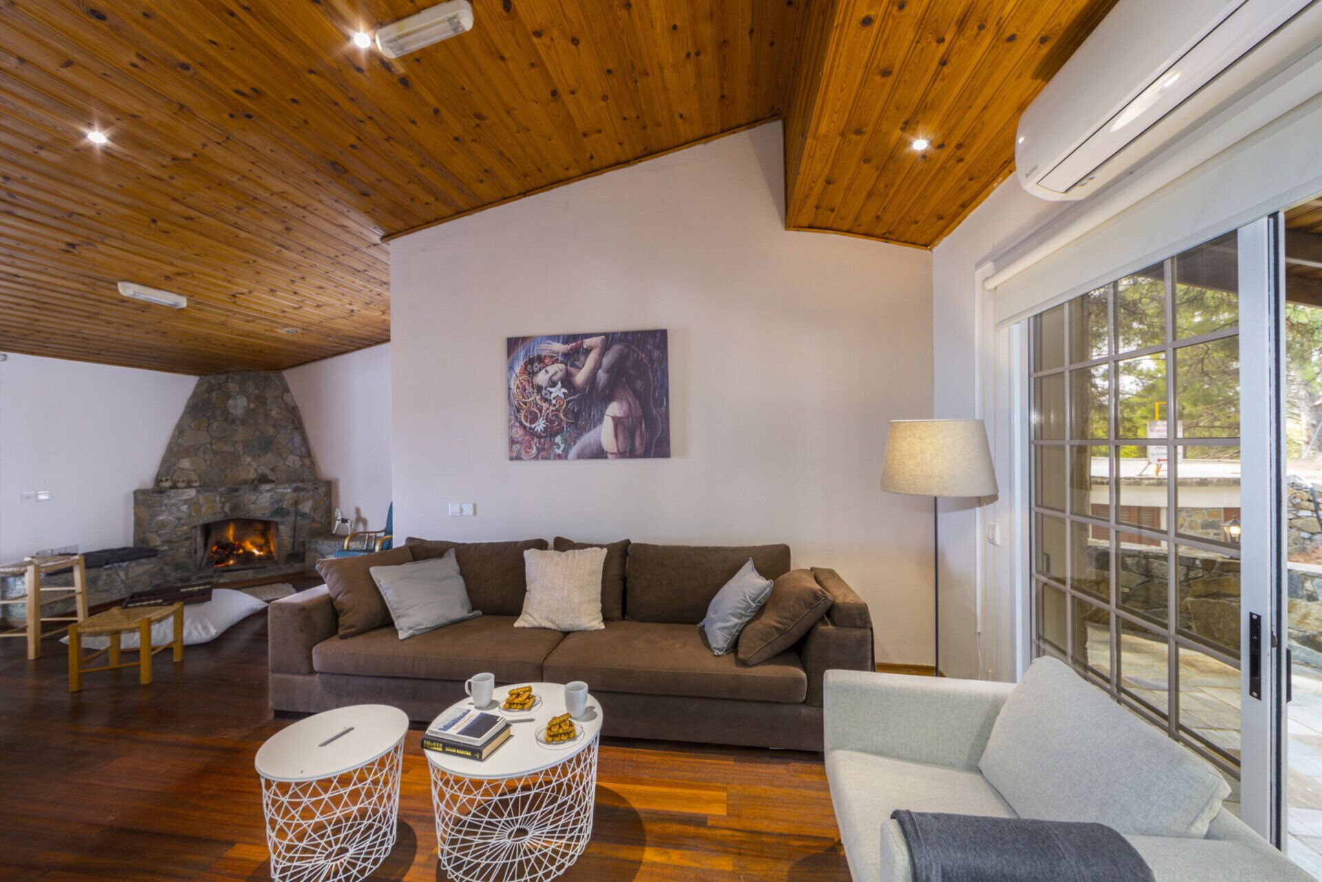 Una sala de estar acogedora con chimenea de piedra, un ventanal grande y un área de descanso confortable.