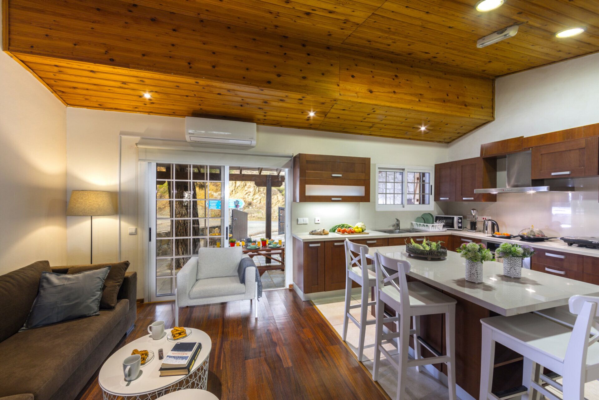 Una cocina moderna con armarios de madera, una isla central y un comedor con sofá y sillas.