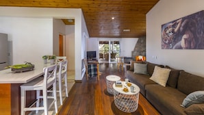 A spacious living area with a wooden ceiling, a dining area with white chairs, a brown sofa, and a painting on the wall. - You and Your Family Will Love This 5 Star Villa With Forest Views, Limassol Villa 1001 (Platres)