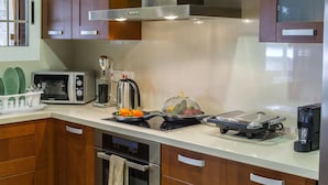 A modern kitchen with wooden cabinets, a microwave, a kettle, a toaster, and a coffee maker. - You and Your Family Will Love This 5 Star Villa With Forest Views, Limassol Villa 1001 (Platres)