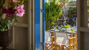 An outdoor dining area with a table set for two, surrounded by chairs.