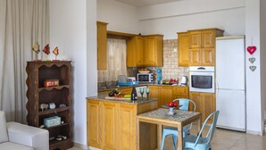 Uma cozinha compacta com armários de madeira, uma ilha central e um espaço de refeições.