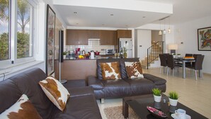 A modern living room with a sofa, coffee table, and a dining area with chairs and a table. - Your Beautiful Holiday Villa Minutes From Beautiful Beaches, Ayia Napa Villa 1370 (Sotira)