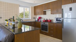 A modern kitchen with wooden cabinets, a stainless steel refrigerator, and a Bosch oven. - Your Beautiful Holiday Villa Minutes From Beautiful Beaches, Ayia Napa Villa 1370 (Sotira)