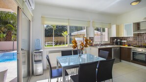 Una cocina moderna con comedor, dispensador de agua y vista al patio trasero.