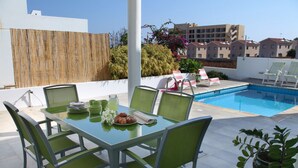 Terraço no telhado com piscina, área de estar ao ar livre e mesa posta para o café da manhã.