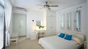 Quarto com cama, escrivaninha, cadeira, guarda-roupa e ventoinha no teto.