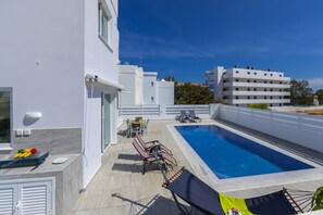 A modern building with a swimming pool, outdoor seating, and a grill area. - At Last You can Rent the Perfect Luxury Villa, Protaras Villa 1494 (Paralimni)
