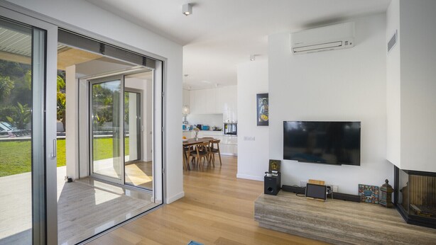 Een moderne woonkamer met een flatscreen televisie, een open haard en een schuifdeur naar een balkon.