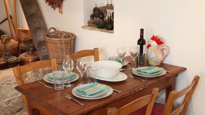 A wooden dining table set with plates, glasses, and a bottle. - Charming Stone Cottage Getaway - Nicosia 1003 (Kalopanayiotis)