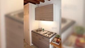 A compact kitchen with wooden cabinets, a built-in stove, and a small countertop. - Charming Stone Cottage Getaway - Nicosia 1003 (Kalopanayiotis)