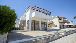 A modern two-story house with large windows, a balcony, and a paved driveway. - Indulge in Luxury Living Steps From the Beach,1419 (Paralimni)