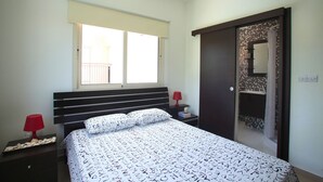 Quarto com cama, duas mesas de cabeceira, uma janela e um guarda-roupa.