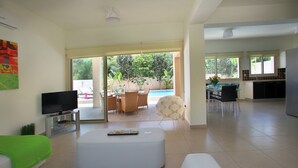 Ampla sala de estar com televisão de tela plana, um sofá e um espaço de jantar com cadeiras e mesa.
