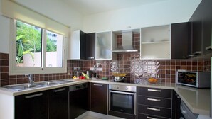 Cozinha moderna com armários escuros, pia de aço inoxidável e forno embutido.