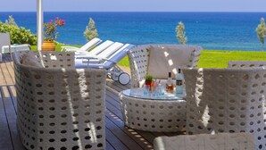 A deck with wicker furniture and a glass table, overlooking a body of water. - You and Your Family Will Love This Beachfront Villa, Protaras Villa 1526 (Paralimni)