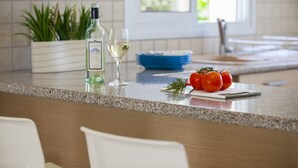 Un comptoir de cuisine avec une bouteille de vin blanc, un verre et des tomates fraîches.