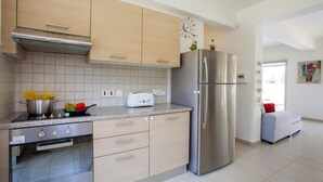 Une cuisine moderne dotée d’appareils électroménagers en acier inoxydable, de meubles de couleur bois clair et d’un revêtement mural en carreaux.