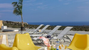 A rooftop terrace with sun loungers, a table with drinks and flowers, and a view of the sea. - The Secret to Enjoying Your 5 Star Villa With Large Private Pool, Protaras Villa 1493 (Paralimni)