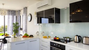 A modern kitchen with white cabinets, a black stove, and a tiled backsplash. - The Secret to Enjoying Your 5 Star Villa With Large Private Pool, Protaras Villa 1493 (Paralimni)