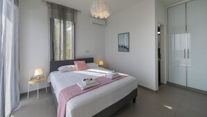 A modern bedroom with a large bed, bedside lamps, a decorative light fixture, and a closet. - The Secret to Enjoying Your 5 Star Villa With Large Private Pool, Protaras Villa 1493 (Paralimni)