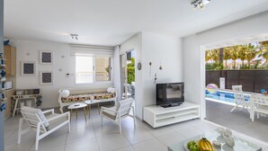 A modern living room with a TV, seating area, and a pool view. - Ultimate Beachside Luxury: Protaras Villa 1461 (Paralimni)