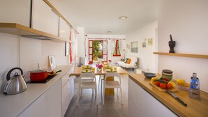 A modern kitchen with white cabinets, a wooden countertop, and a dining area with white chairs. - Discover Perfect Holiday Escape in Protaras, 1411 (Paralimni)
